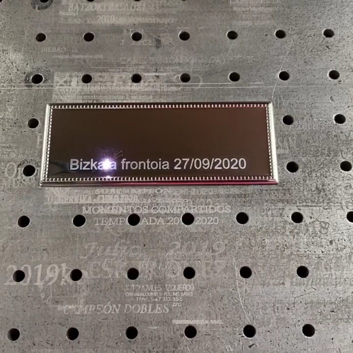 Placa reci&eacute;n grabada sobre la mesa del l&aacute;ser del taller